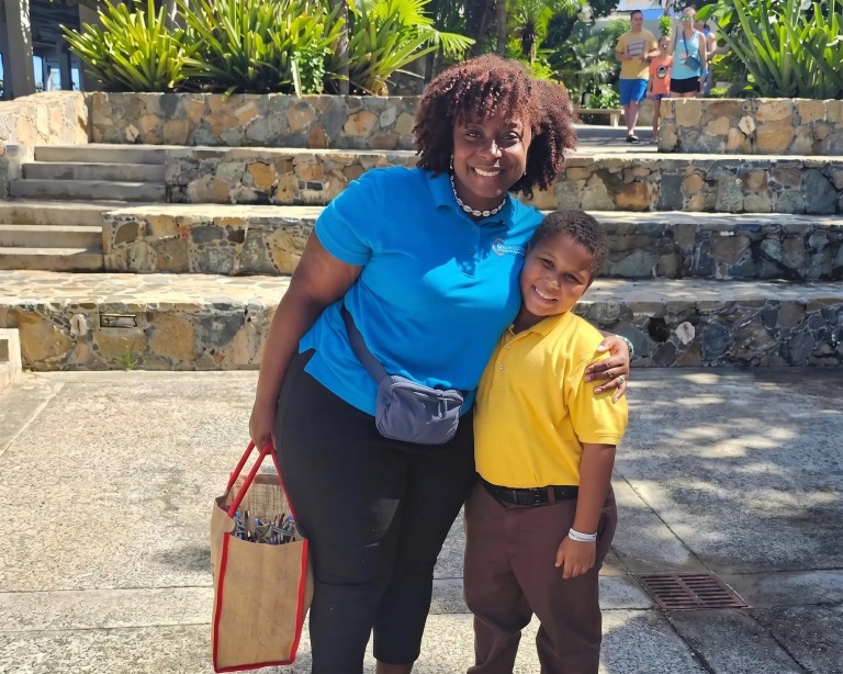 Woman and child smiling outdoors, standing on a stone walkway.