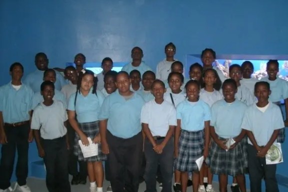 Group of students in uniforms standing in front of a blue wall.